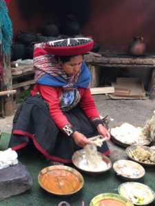 Peruanische Frau, die in traditionellen Schüsseln kocht