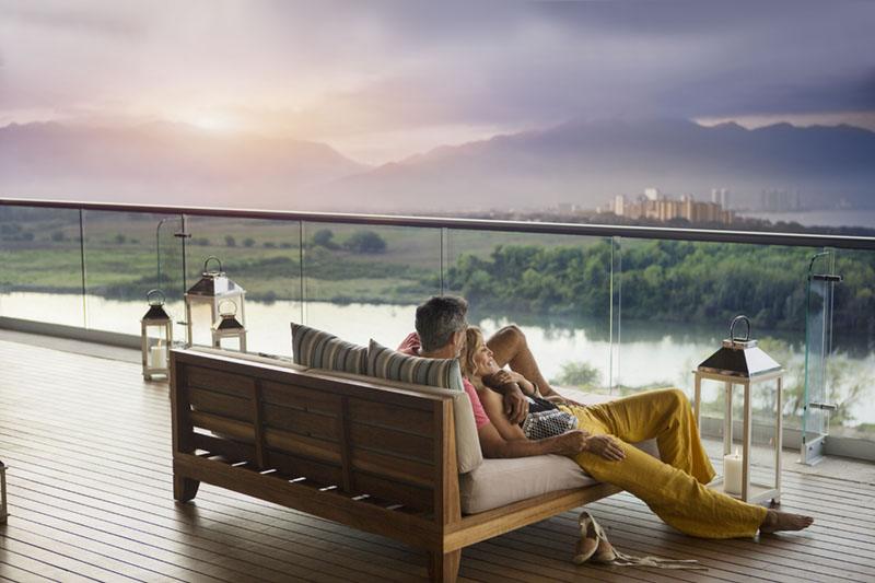 Casal relaxando no deck com vista para a água durante as férias
